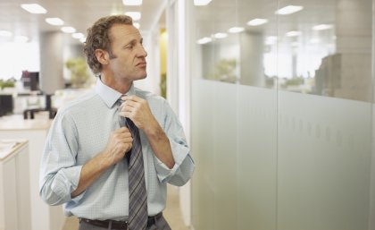 Businessman fixing his tie whilst looking at his reflection in a window